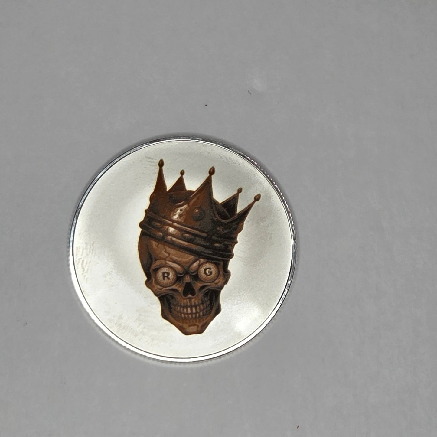 Metallic insect figurine on a reflective silver disc against a gray background