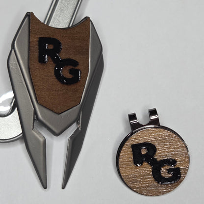 Golf divot tool and hat clip with 'RC' logo on a light gray background