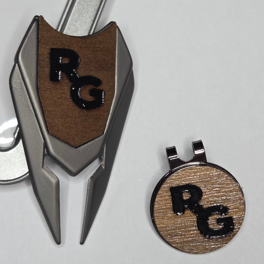 Golf divot tool and hat clip with 'RC' logo on a light gray background